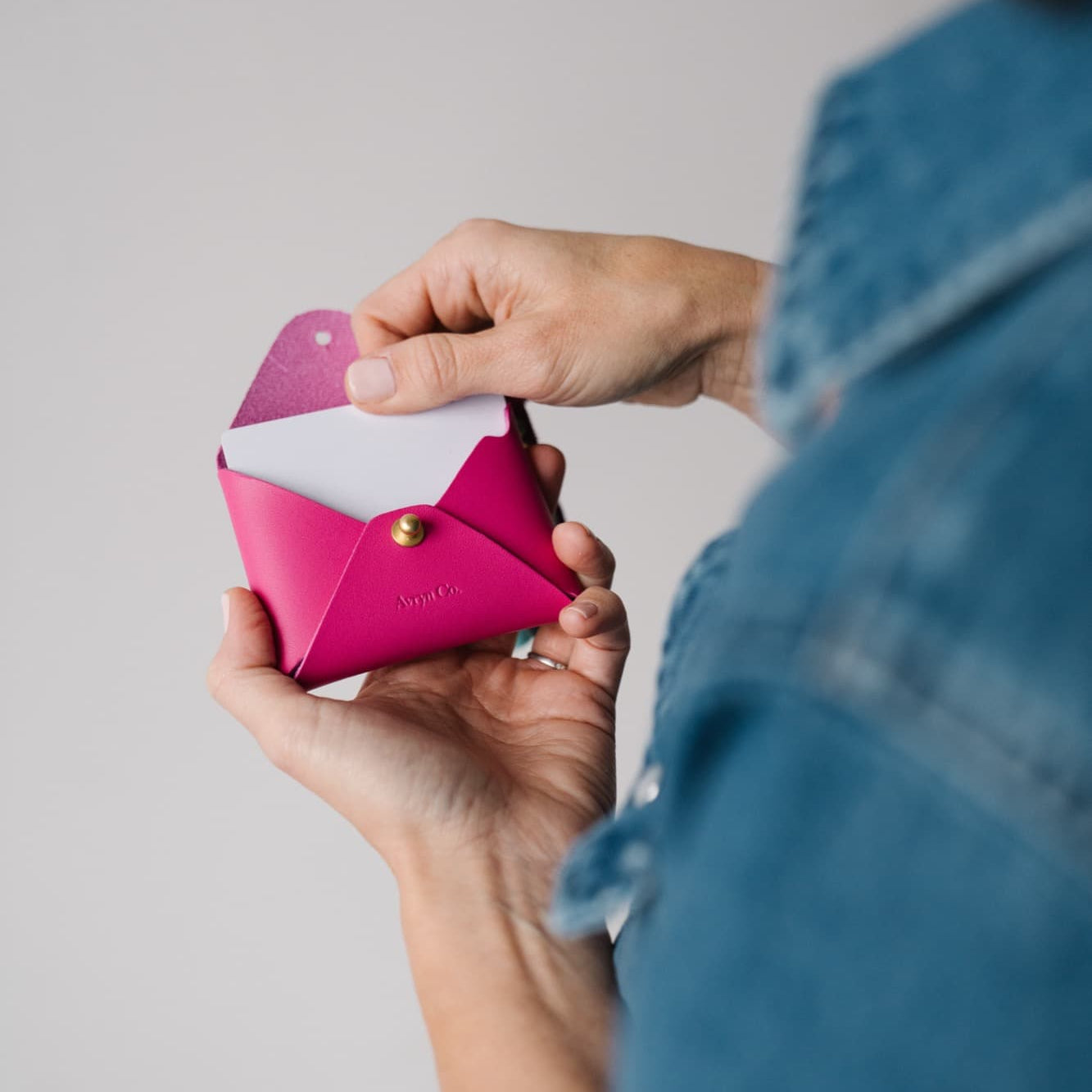 Person holding a pink wallet with a white interior against a neutral background
